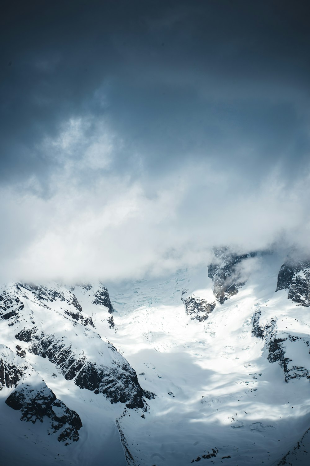 a mountain covered in snow under a cloudy sky