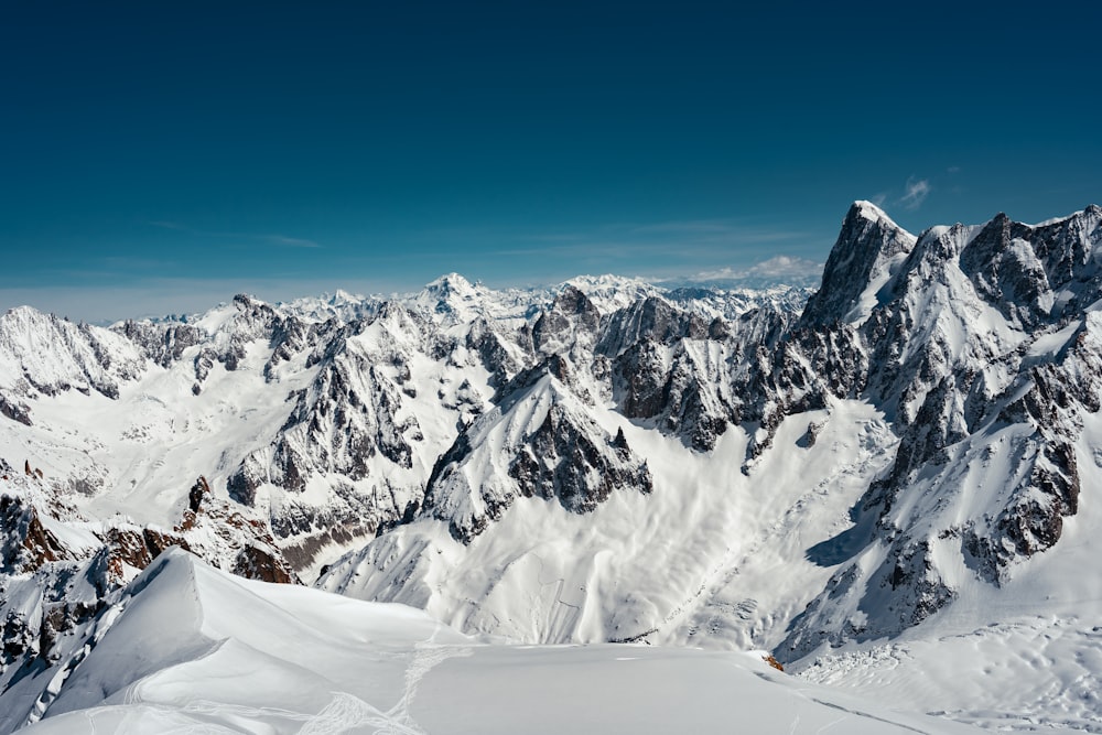 a view of a snowy mountain range from the top of a mountain