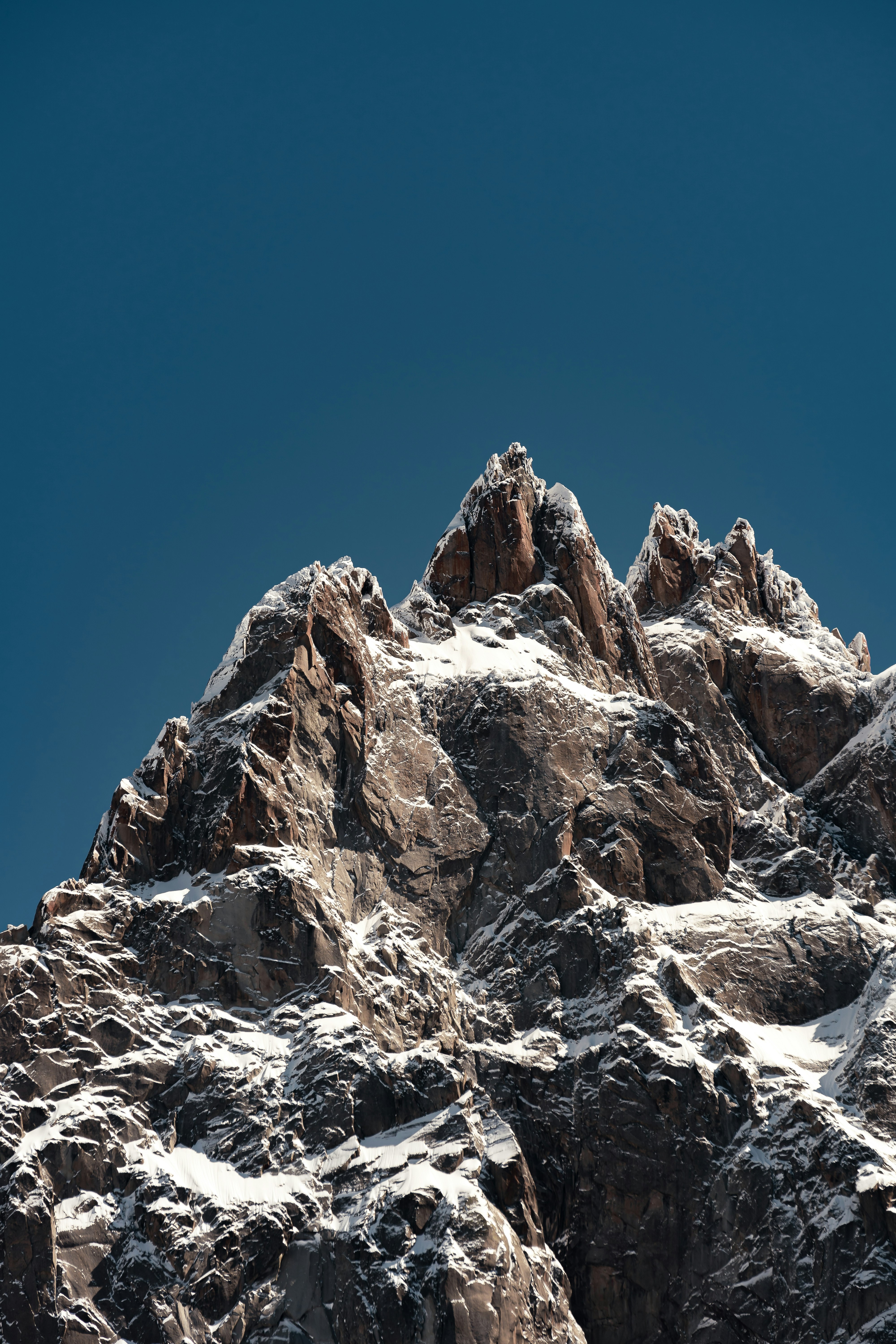 A very tall mountain covered in snow under a blue sky photo – Free ...