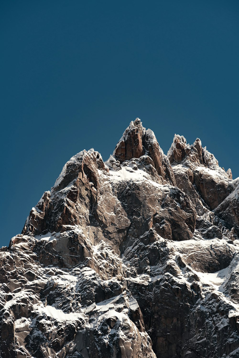 a very tall mountain covered in snow under a blue sky