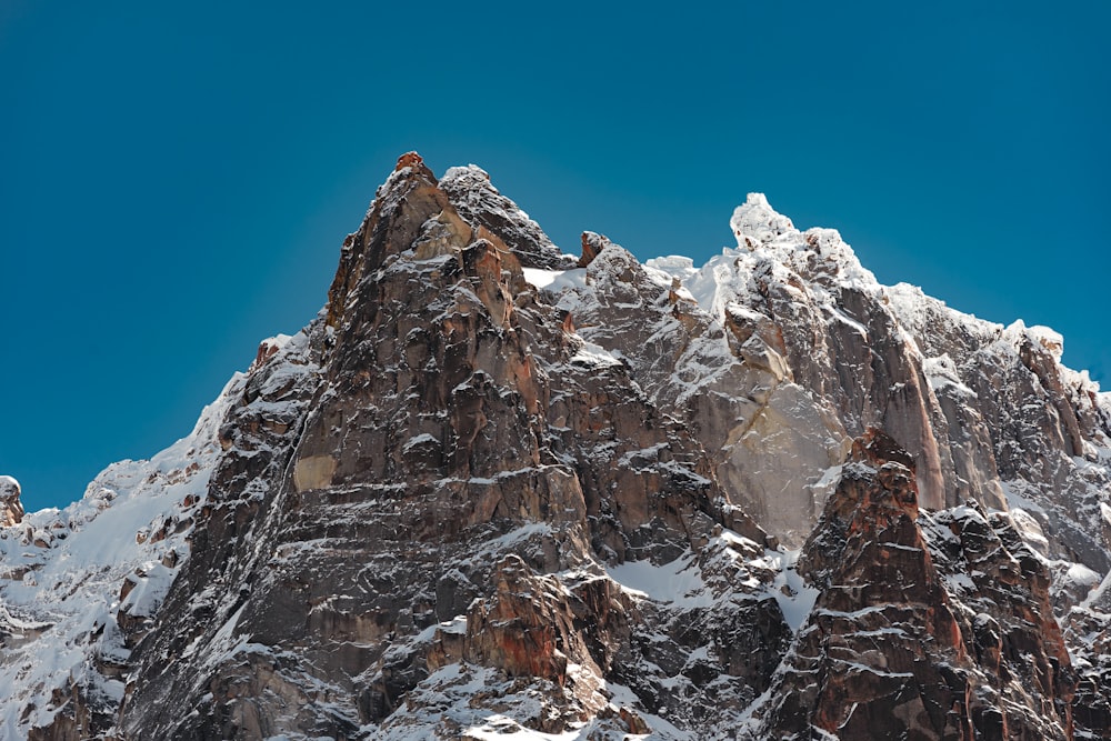 a very tall mountain covered in snow under a blue sky