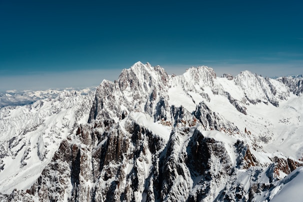 Stunning panoramic view of the Atlas Mountains dusted with snow under a clear blue sky.