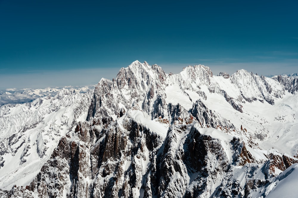 a mountain range covered in snow under a blue sky