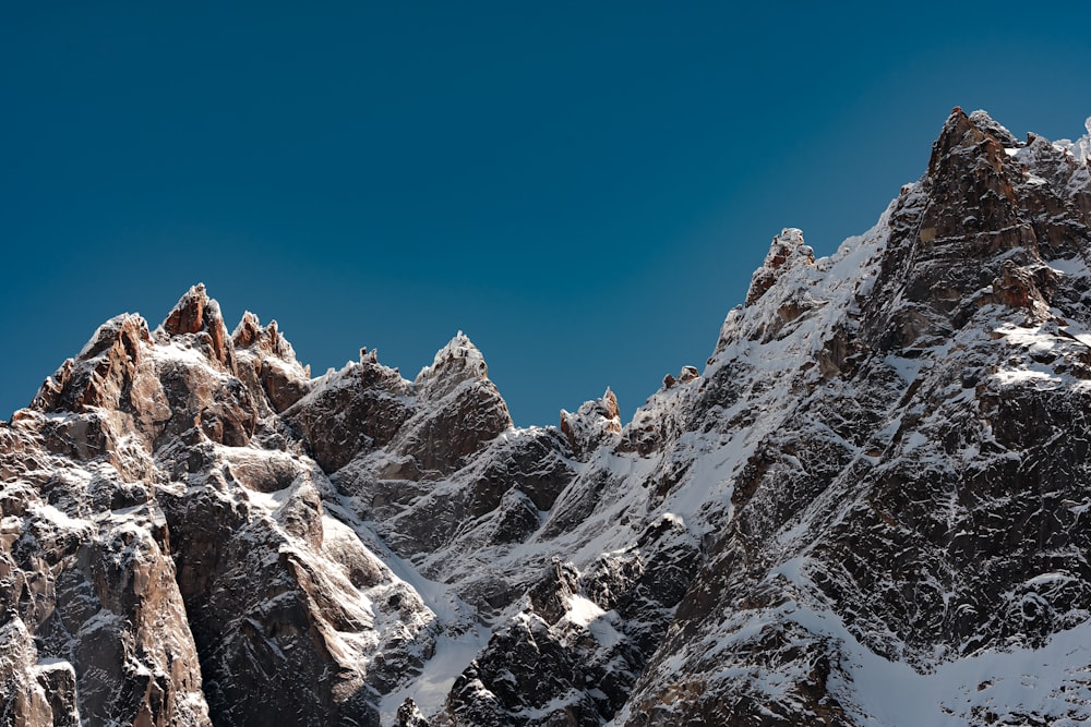 a group of mountains covered in snow under a blue sky