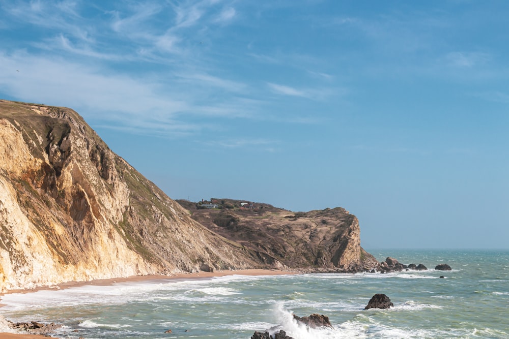 a sandy beach next to a cliff on a sunny day