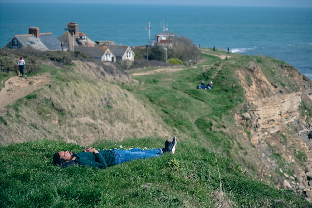 a man laying on top of a lush green hillside