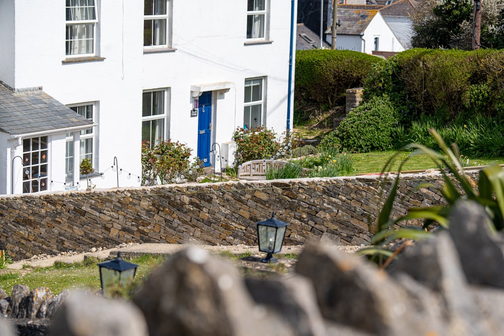 a white house with a stone wall in front of it