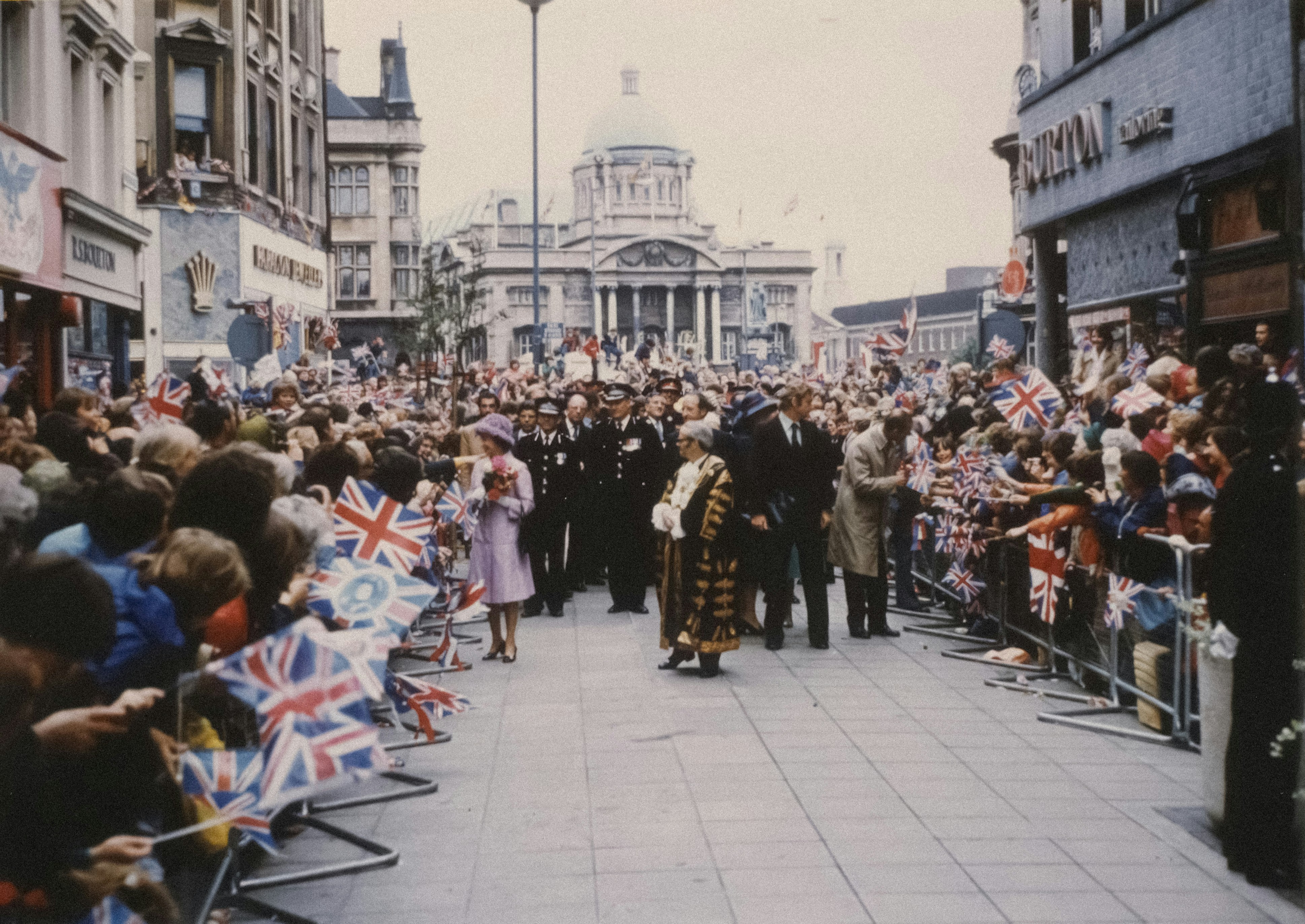 a crowd of people walking down a street next to tall buildings
