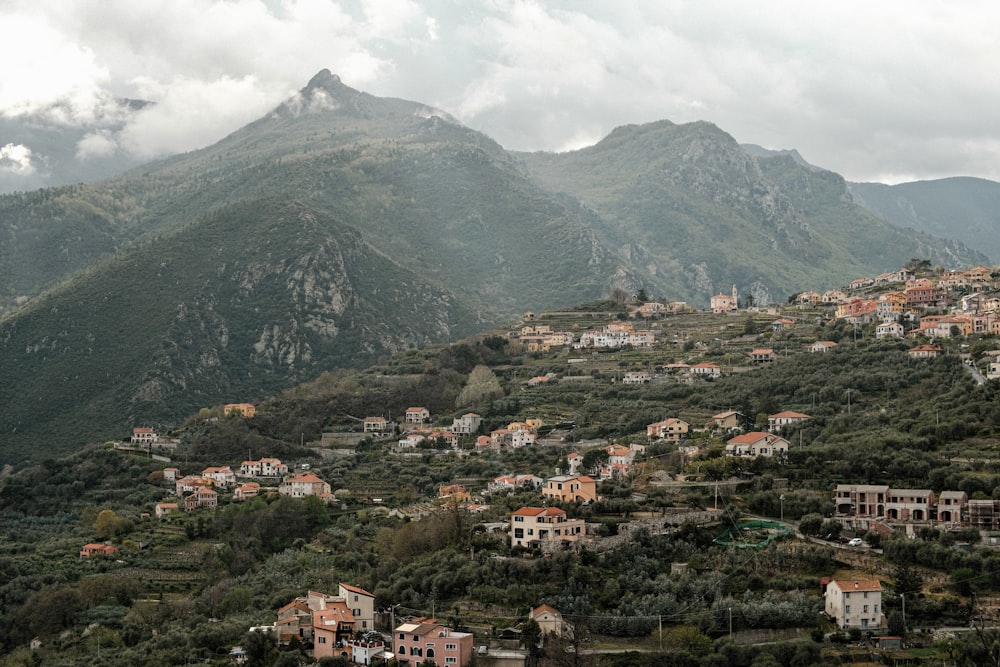 a small village nestled on a hillside with mountains in the background