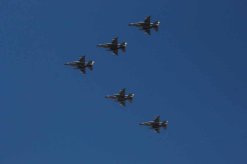 a group of fighter jets flying through a blue sky