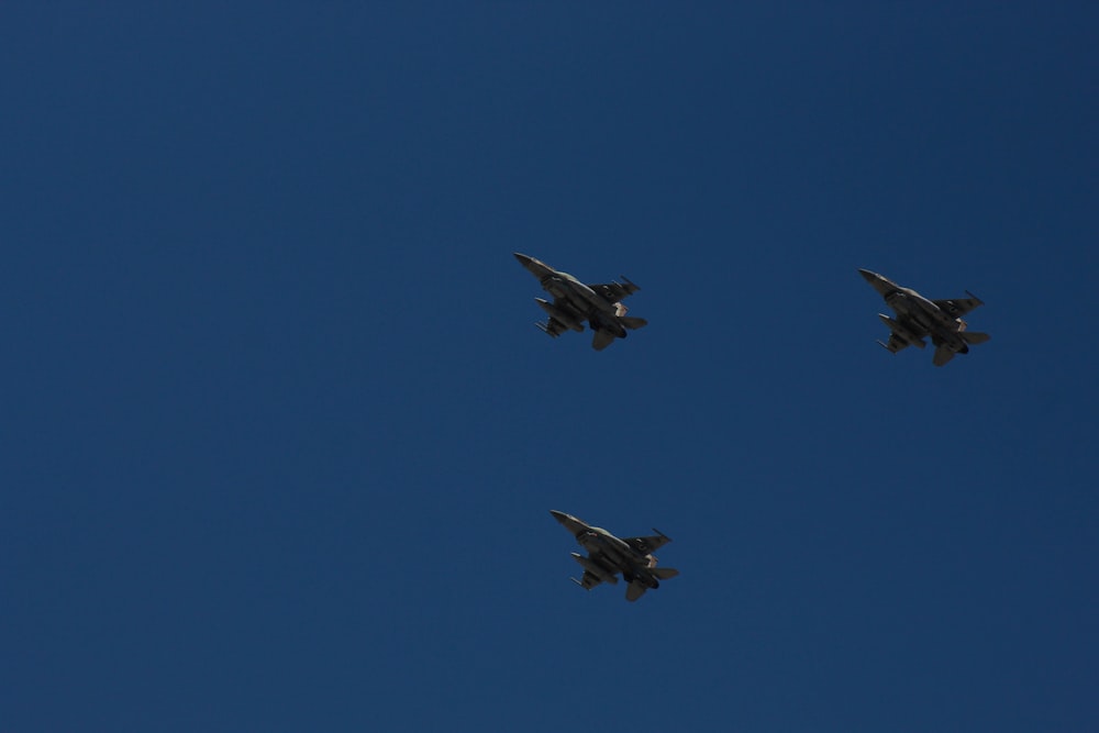 a group of four jets flying through a blue sky