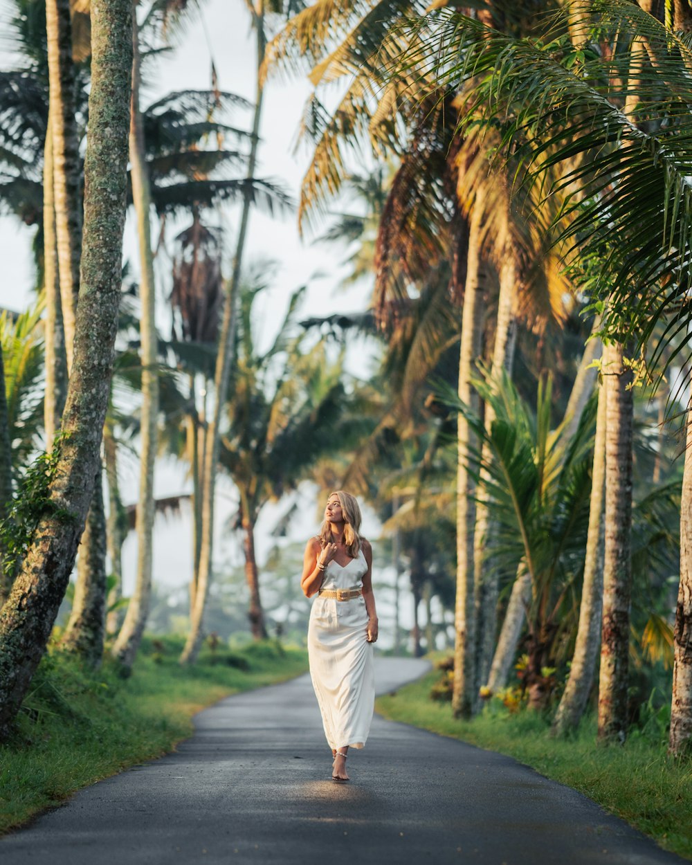 a woman in a white dress walking down a road