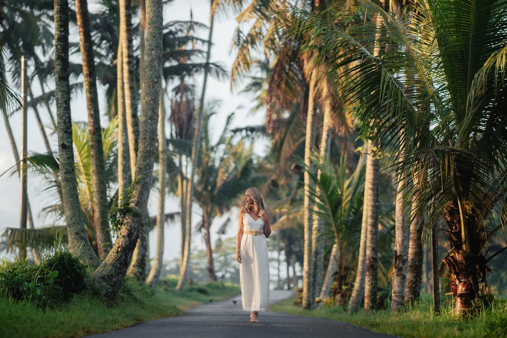 a woman in a white dress is walking down the road