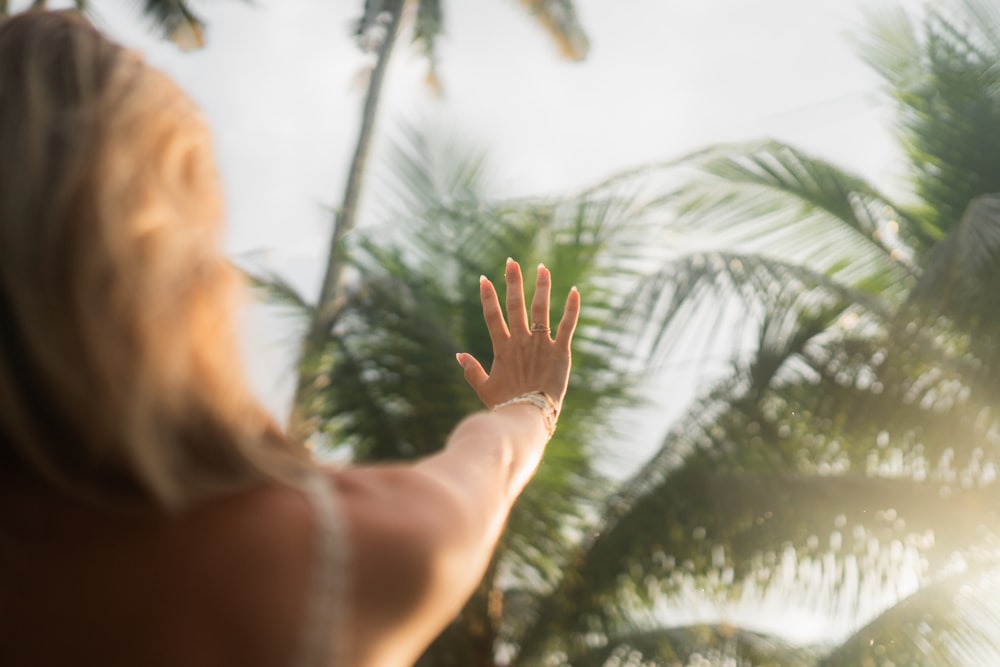 a woman reaching up into the air to catch a frisbee