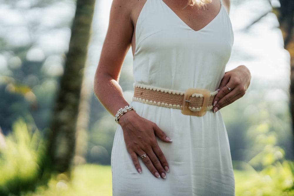 a woman in a white dress is holding a belt