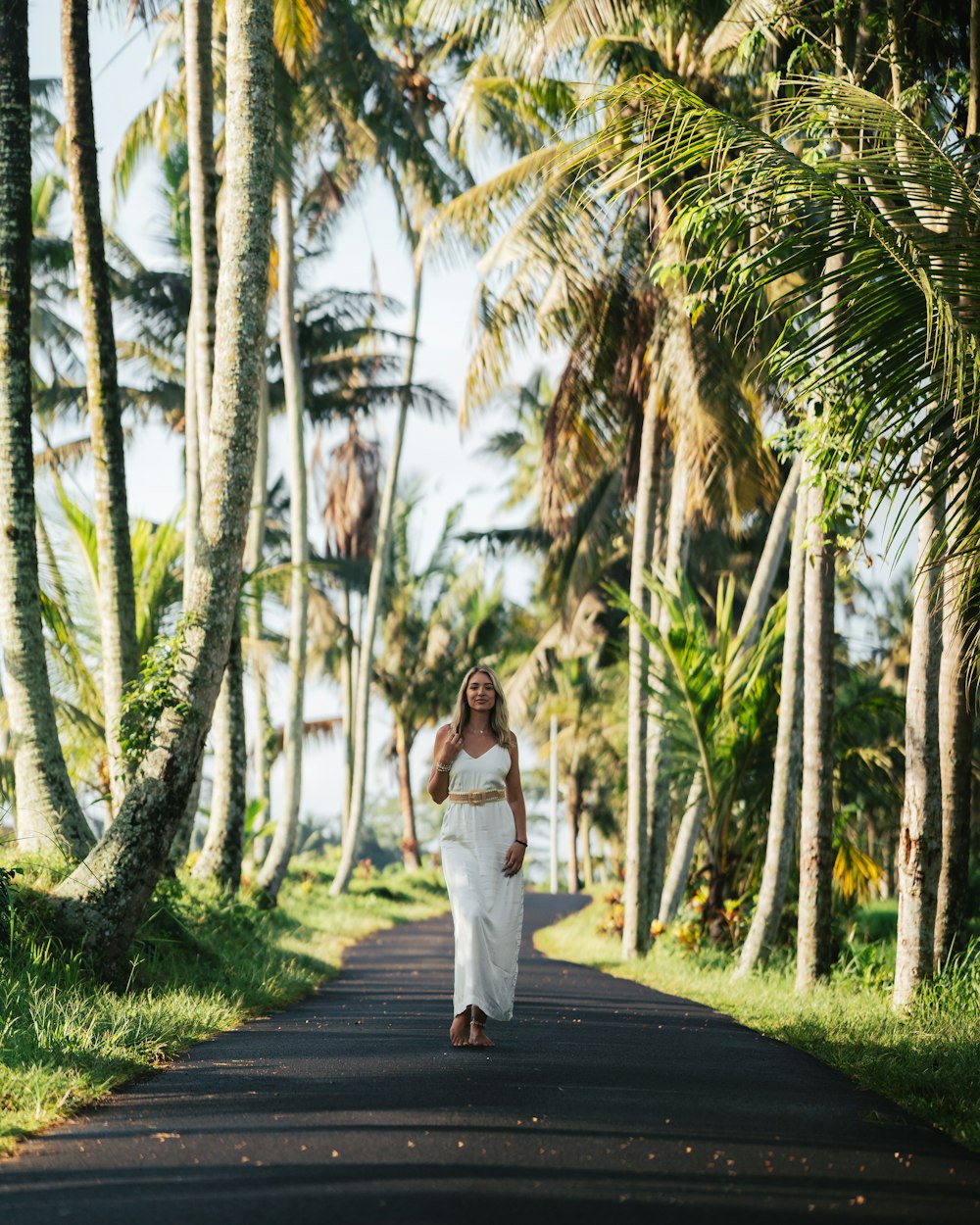 a woman in a white dress walking down a road