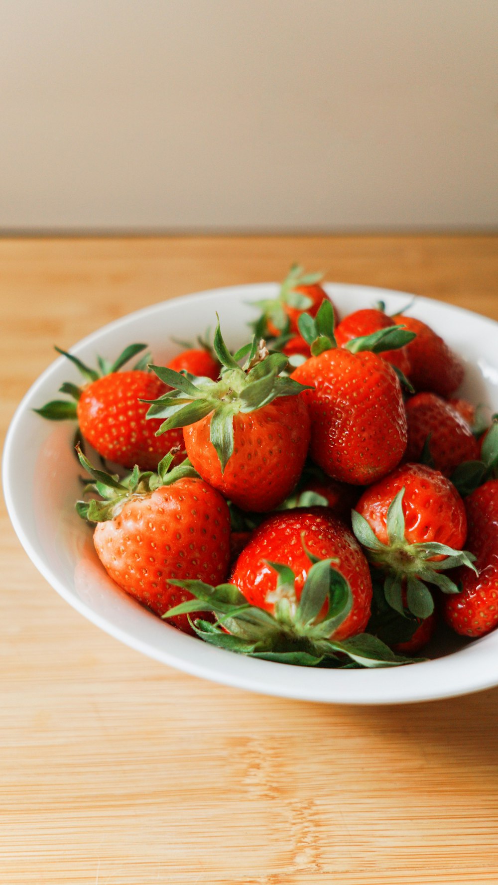 a white bowl filled with lots of ripe strawberries