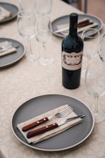 A beautifully arranged table with wine glasses and an elegant bottle of red wine.
