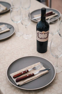 A set of elegant wine glasses arranged neatly beside a bottle of red wine on a rustic wooden table
