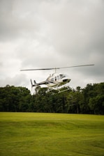 a helicopter flying over a lush green field