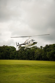 a helicopter flying over a lush green field
