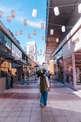 A vibrant high-street retail scene with modern shopfronts and bustling foot traffic under a clear sky.
