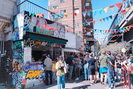 A lively scene of people wearing Retroviva 80s-inspired t-shirts in a colorful urban setting.