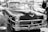 A classic vintage car is prominently displayed in a parking lot, surrounded by other vehicles. The car showcases distinct chrome detailing and a polished exterior. A license plate with the text 'PH 50WAY' is visible at the front. The windows display various signs, hinting at a car show or gathering.