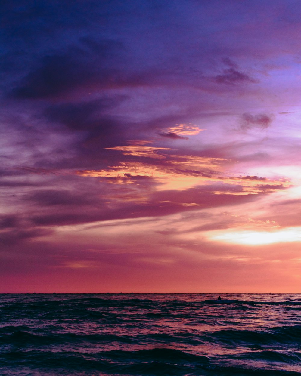 a person riding a surfboard in the ocean at sunset