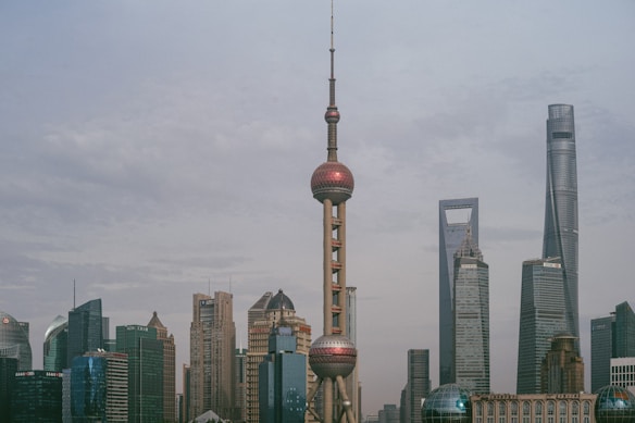 A cityscape featuring a skyline dominated by modern skyscrapers, including a tower with distinct spheres near the top and other towering structures with futuristic designs.