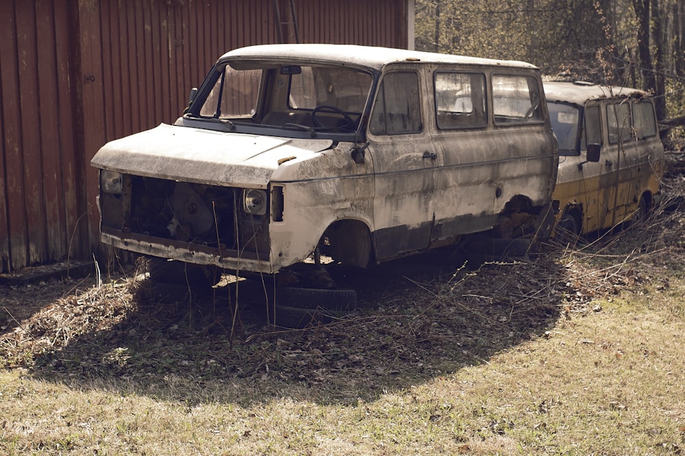 an old van sitting in a field next to a building