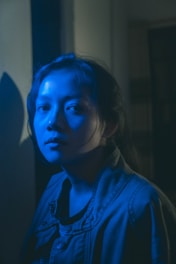 A moody, dark frame from a music video featuring deep blue lighting and dynamic shadows.