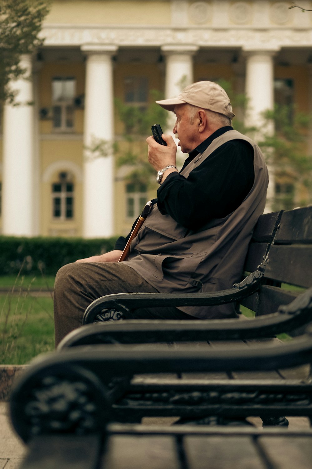 Un hombre sentado en un banco con un teléfono celular en la mano