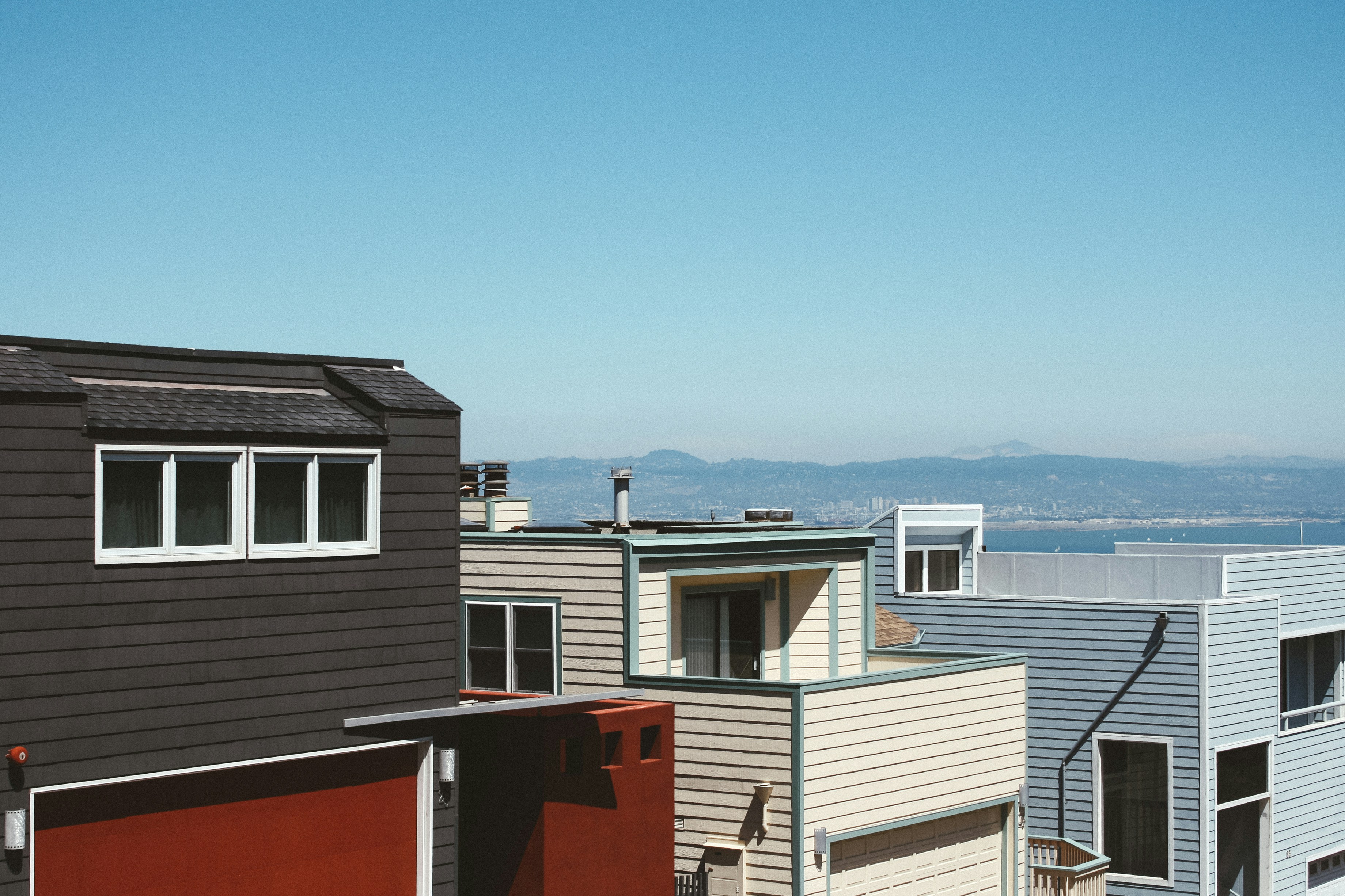 Rangée de maisons victoriennes colorées typiques avec une montagne en arrière plan sous le soleil.