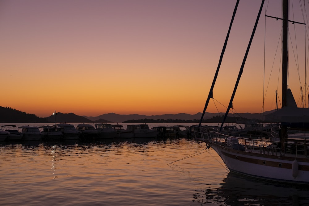 a sailboat is docked in the water at sunset