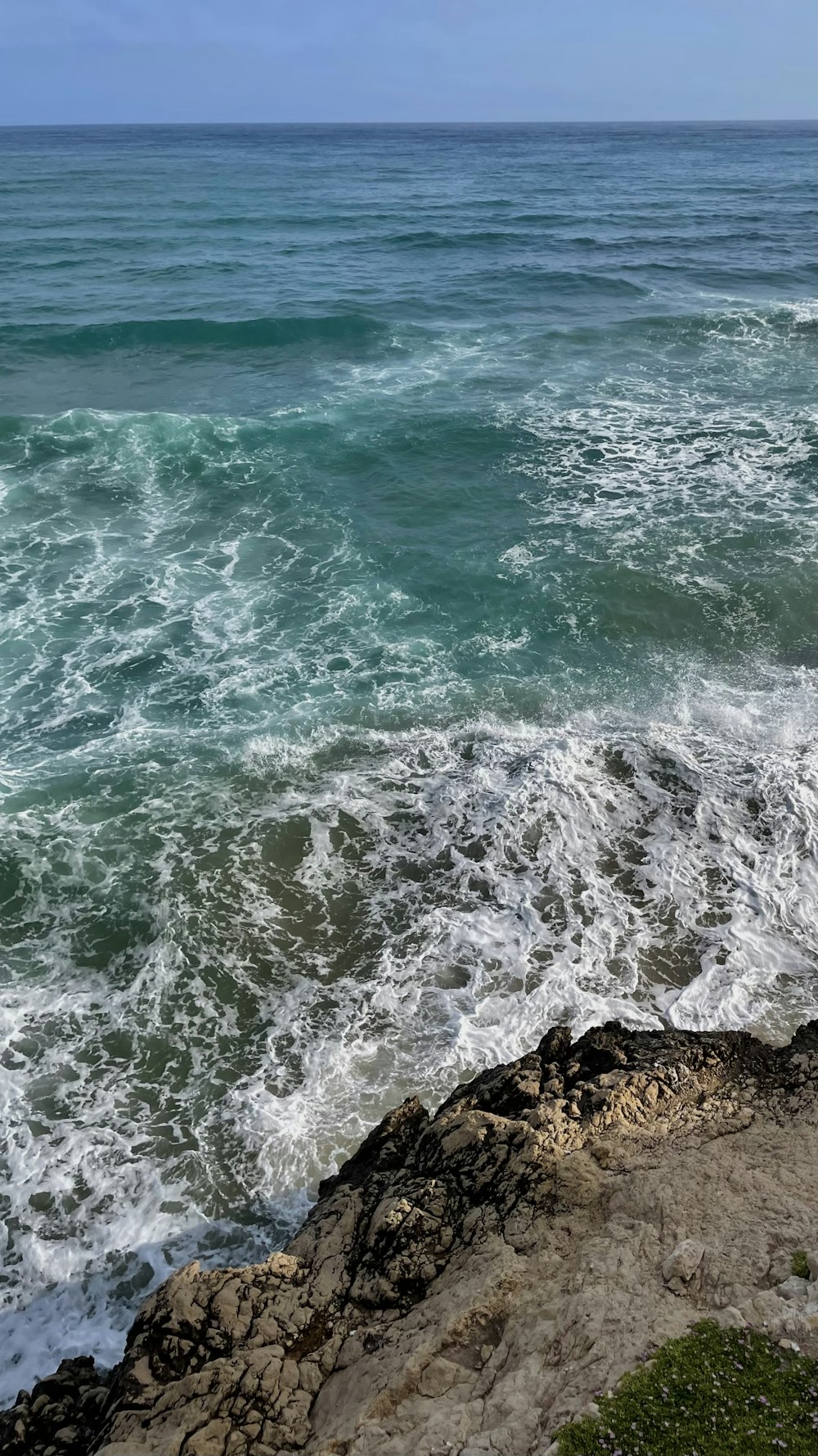 a person standing on top of a cliff near the ocean