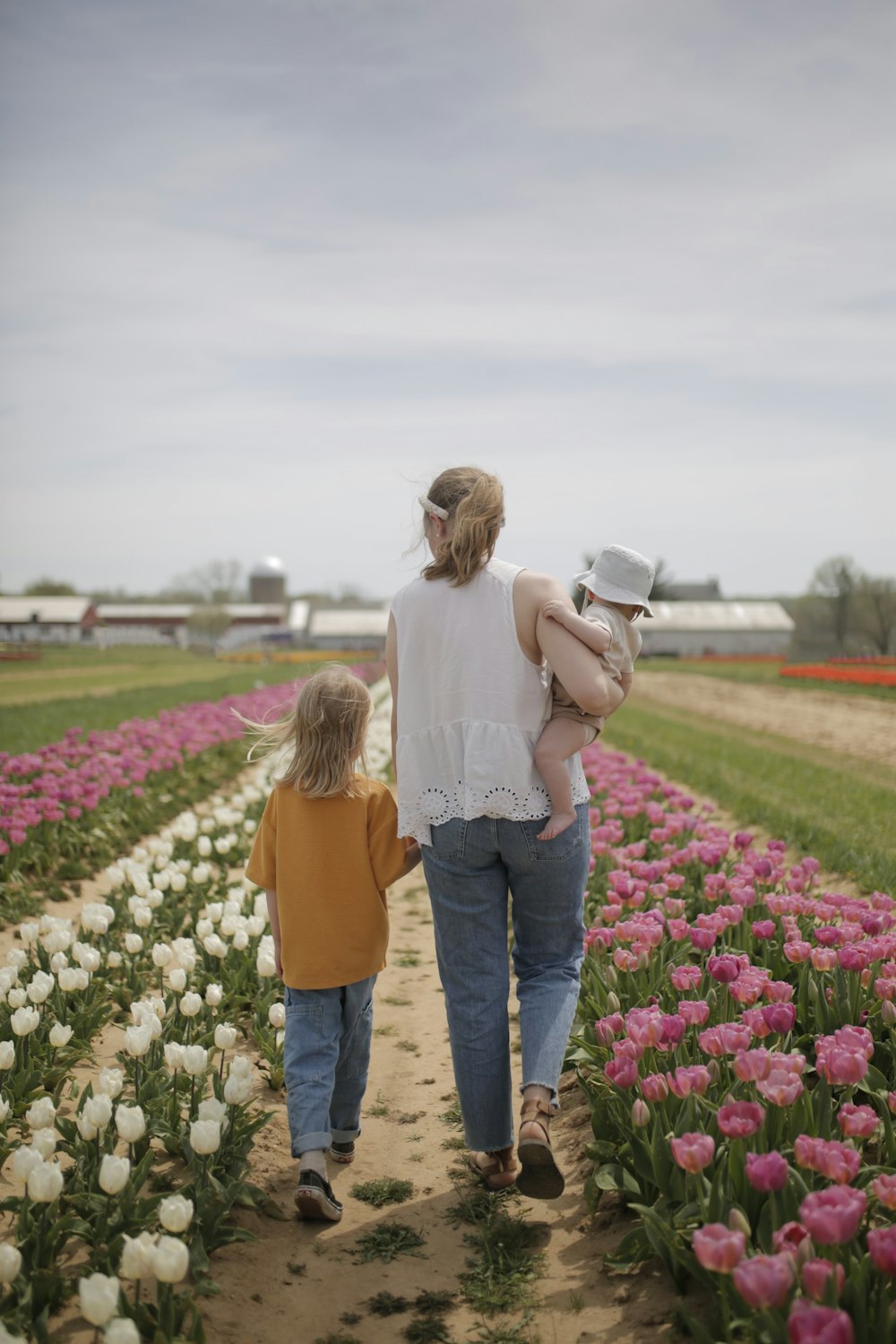 a woman and child walking through a field of flowers