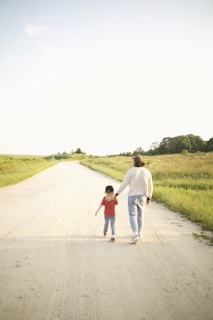 Serene photo of a parent and child holding hands while walking through a quiet garden in morning light.