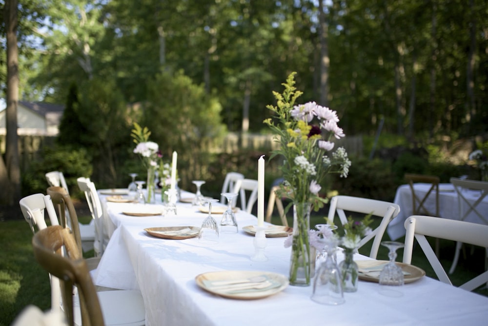 a long table with white table cloths and flowers in vases