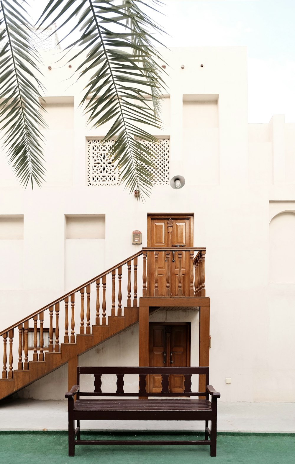 a wooden bench sitting in front of a white building