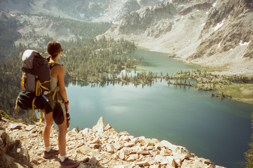 a woman with a backpack looking at a lake