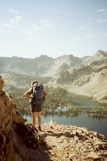 A sleek backpack resting on a rocky mountain ledge overlooking a serene alpine lake at dawn.