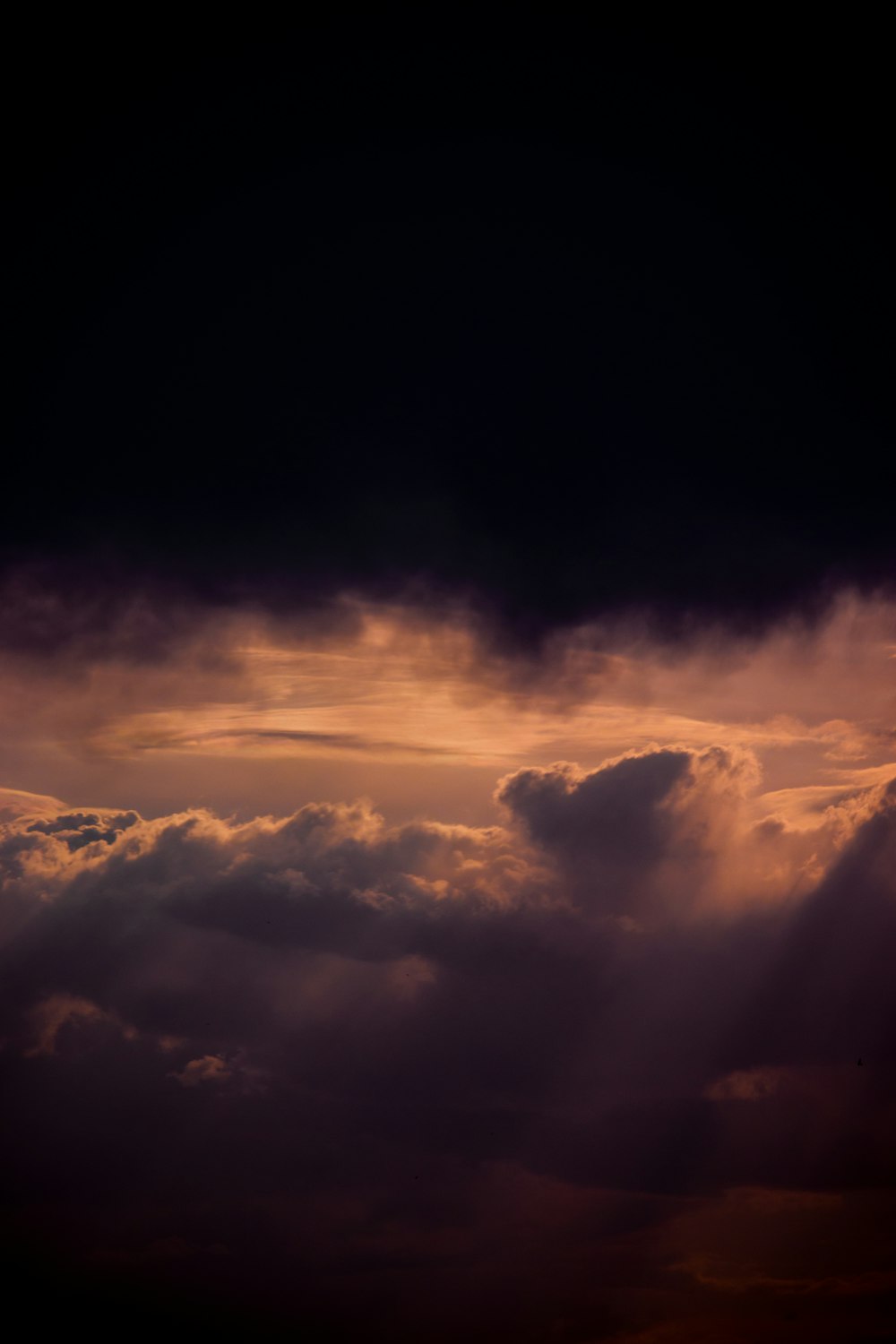 a plane flying through a cloudy sky at sunset