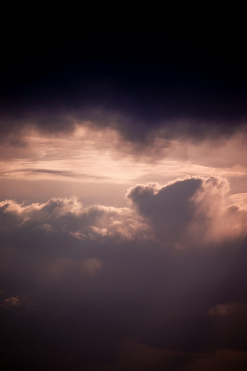 a plane flying through a cloudy sky at sunset