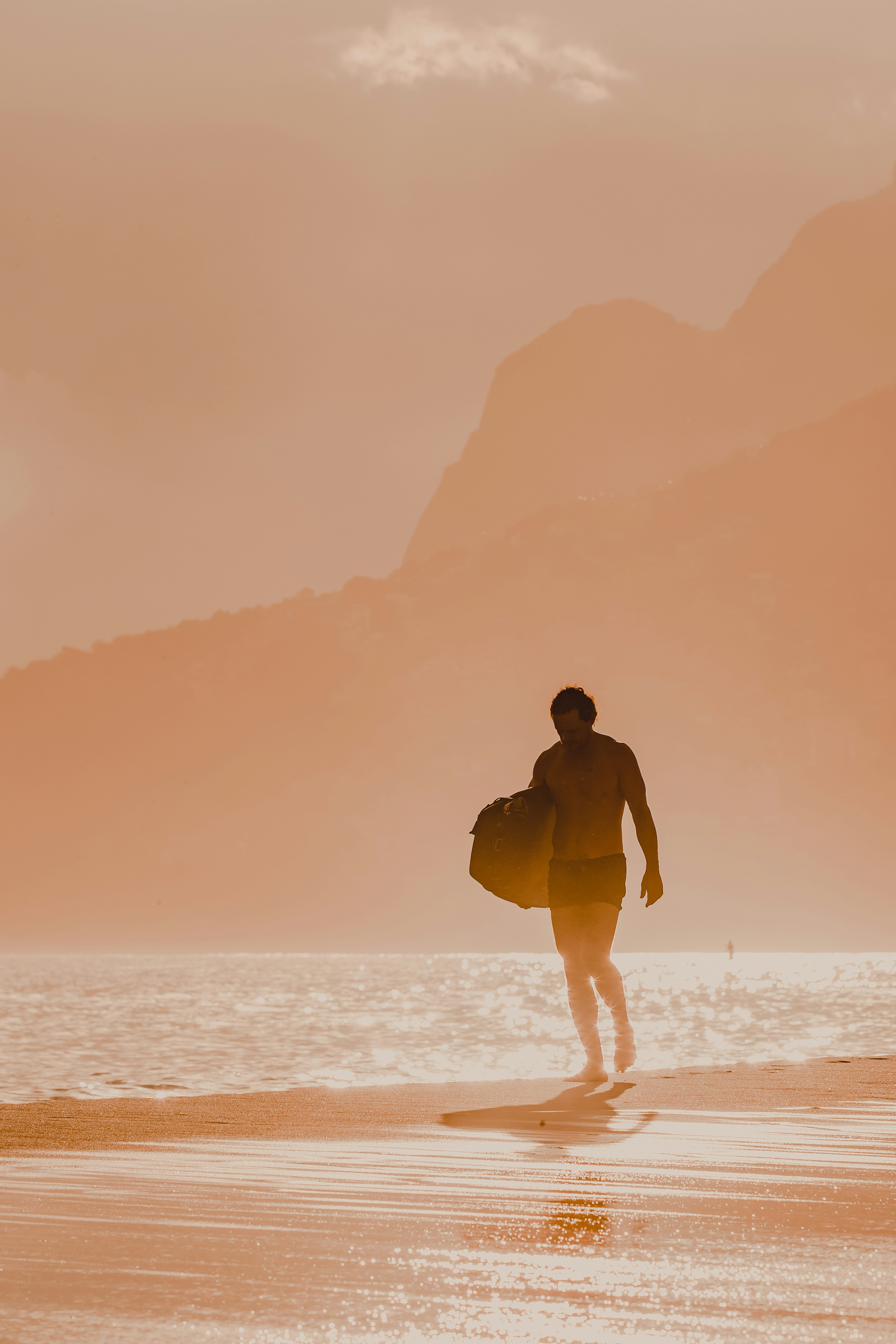 a man with a surfboard walking on the beach