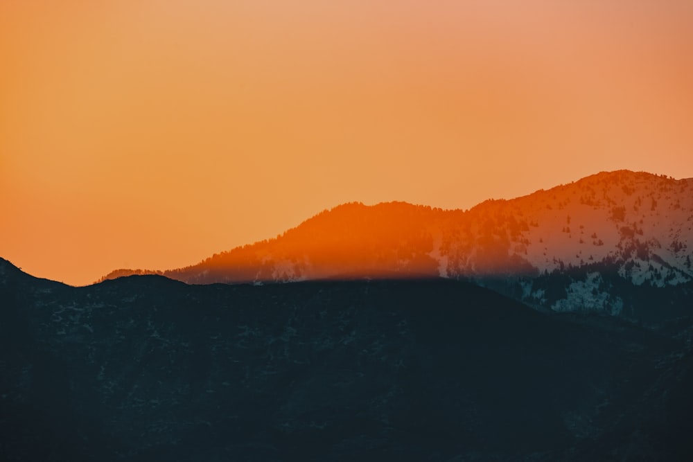 une vue d’une chaîne de montagnes avec le coucher de soleil en arrière-plan