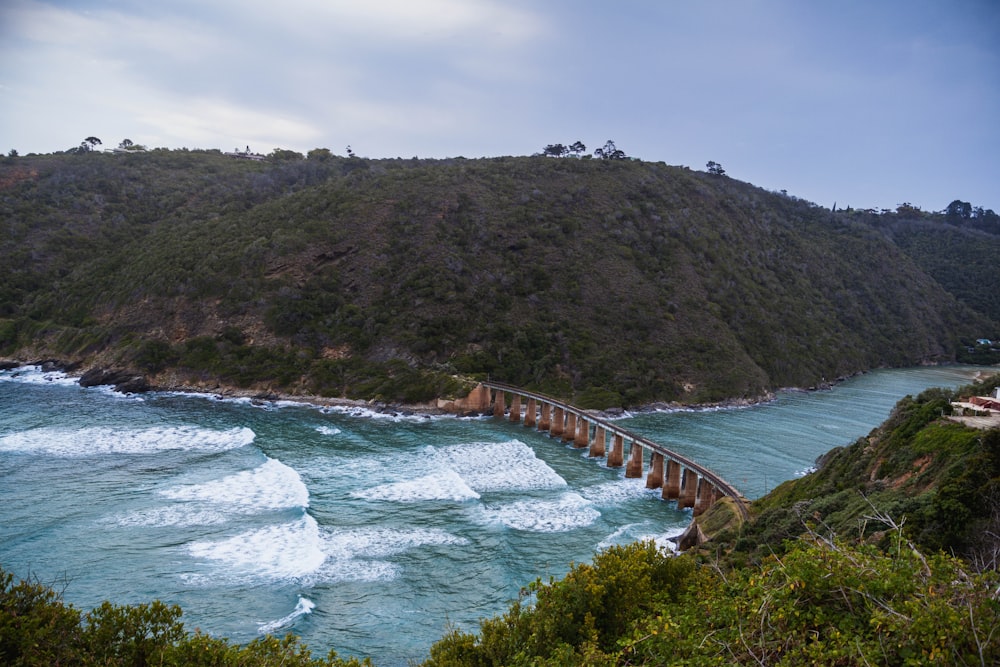 a bridge over a body of water near a mountain