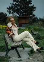 A serene outdoor scene with a model seated on a bench, wearing a chic blazer from the collection.