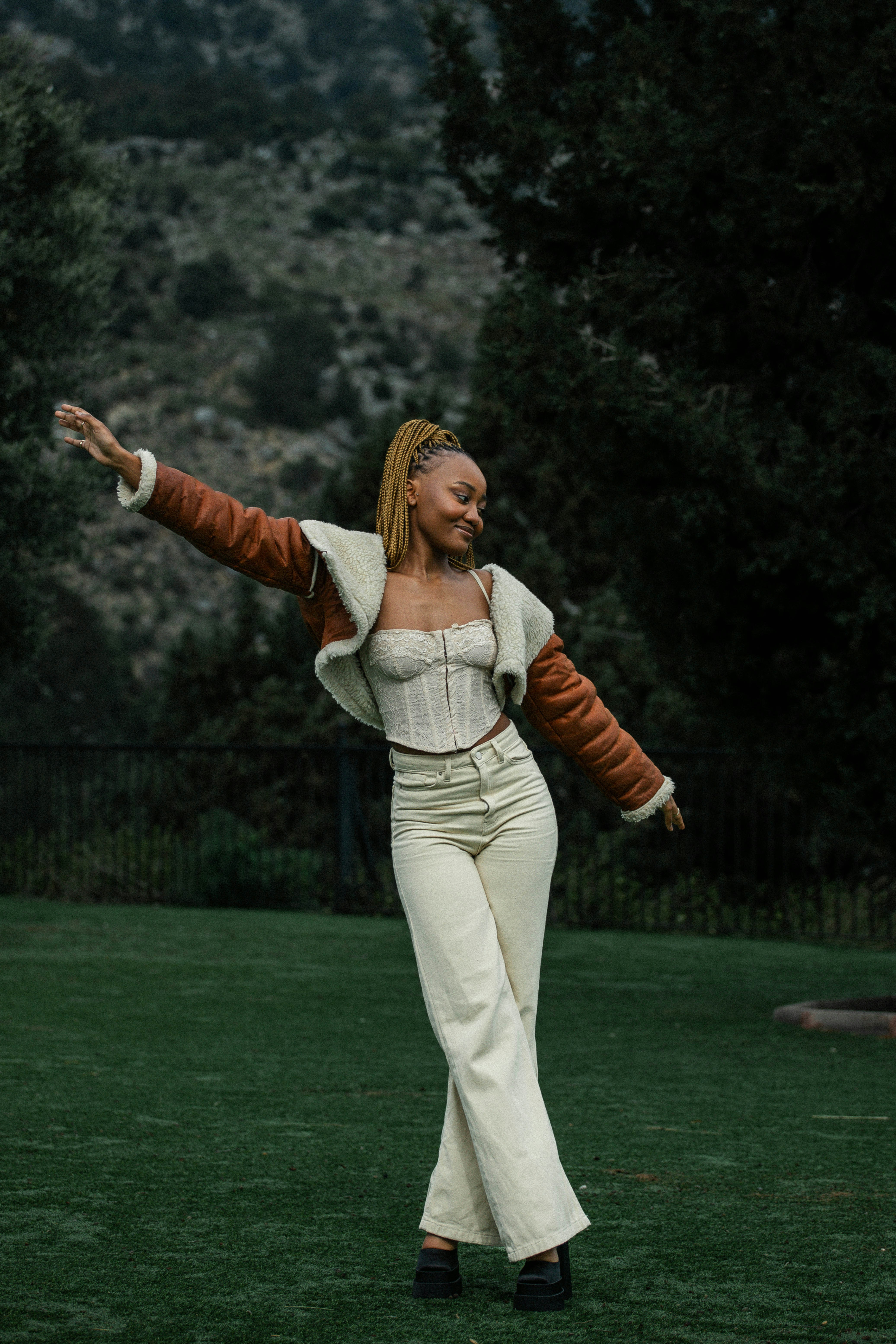 a woman in white pants and a brown jacket