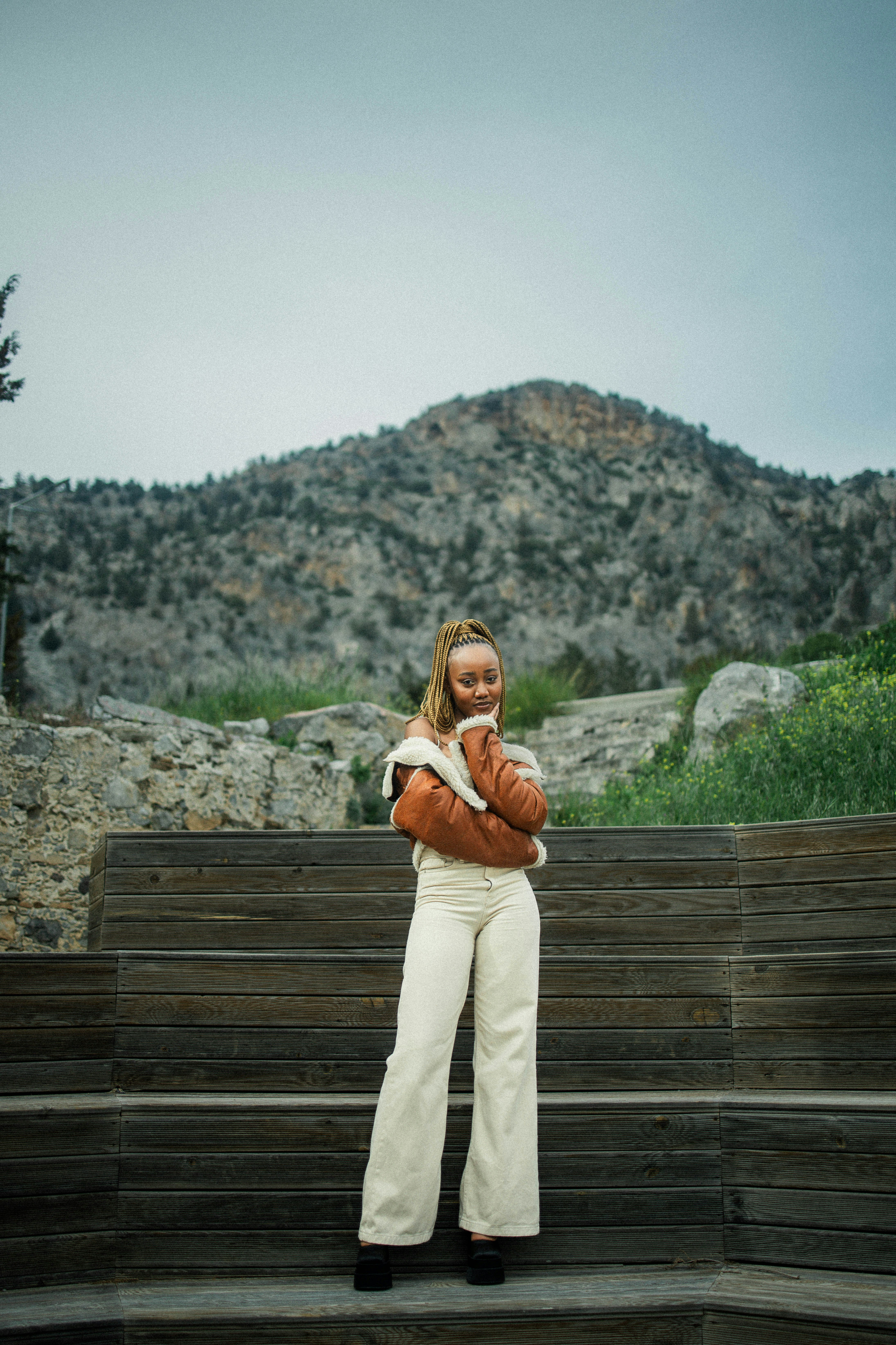 a woman standing on a wooden bench in front of a mountain